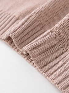 Detailed close-up of pink knit sweater showing ribbed cuffs and soft fabric texture