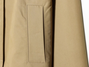Close-up of khaki short trench coat featuring twill fabric and reinforced pocket stitching