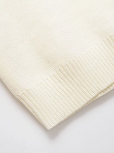 Close-up of cream-colored knit vest showing ribbed edge and soft textured fabric detail
