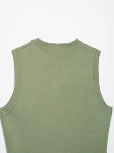 Detail of sage green knitted vest featuring fine ribbing at the neck and armholes