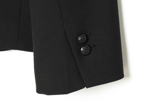 Close-up of black blazer cuff featuring ornate lion head embossed buttons on fabric