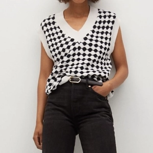Close-up of black and white checkered knitted vest showing V-neck and thick texture