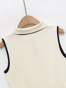 Detailed close-up of cream knit vest featuring black contrast trim on the neckline