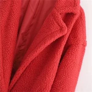 Close-up of red teddy faux fur coat featuring a large lapel and thick textured fabric