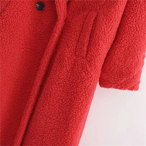 Macro shot of red teddy faux fur texture with a black button and side pocket detail