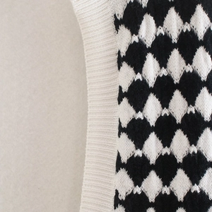 Macro shot of argyle knit pattern and ribbed hem detailing on a V-neck sweater vest