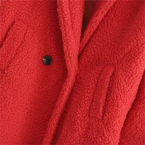 Detailed macro view of red faux fur teddy coat texture with black button and pocket