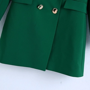 Close-up of deep green blazer featuring smooth fabric texture and golden metal buttons