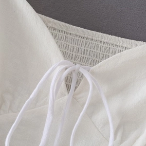 Detail eines weißen Crop-Tops aus Baumwolle mit Smok-Textur und Schnürung vorne