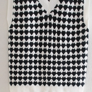 Close-up of V-neck knitted vest showing black and white argyle pattern and ribbed texture