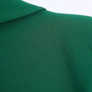Detailed macro view of the dark green blazer collar showing twill fabric texture