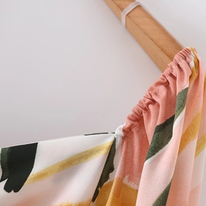 Detail of colorful floral printed dress showing smocked shoulder and lightweight woven fabric