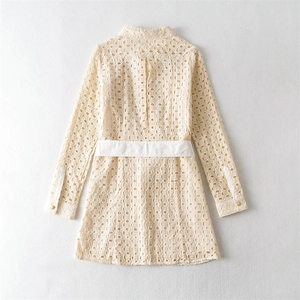 Detail des weißen Broderie Anglaise Kleids mit Stickereien und goldenen Knöpfen am Ärmel