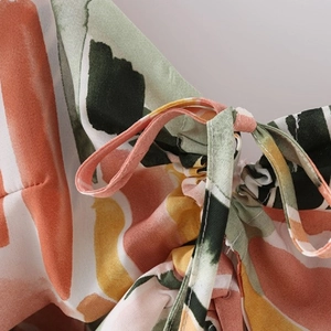 Detail of vibrant abstract print dress with orange and green tie-up drawstring textures