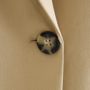 Detailed close-up of khaki twill fabric and premium tortoise shell button on vest