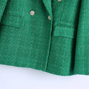 Close-up of green tweed blazer featuring textured weave and decorative metal buttons