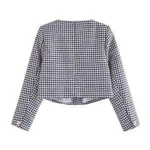 Detailed view of the houndstooth tweed texture and elegant pearl button cuffs on jacket