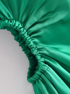 Nahaufnahme von smaragdgrünem Satinstoff mit eleganten, elastischen Kräuselungsdetails