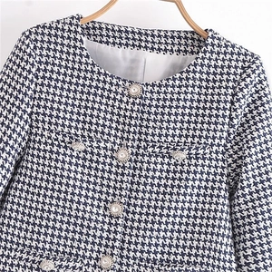 Navy and white houndstooth tweed jacket with decorative crystal buttons on a hanger