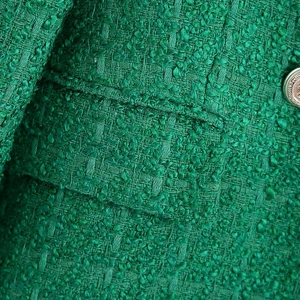 Detail of green tweed fabric texture with a vintage embossed silver metal button