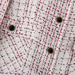 Close-up of woven tweed jacket fabric with elegant gold-rimmed black buttons