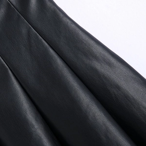 Makroansicht der plissierten schwarzen Kunstleder-Minirock-Details mit feiner Lederstruktur