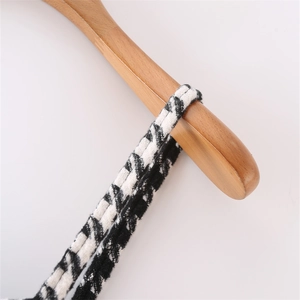 Detail of houndstooth wool dress strap on wooden hanger with textured fabric weave
