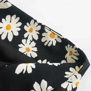 Detailaufnahme des hochtaillierten Rocks mit Gänseblümchen-Print auf schwarzem Stoff