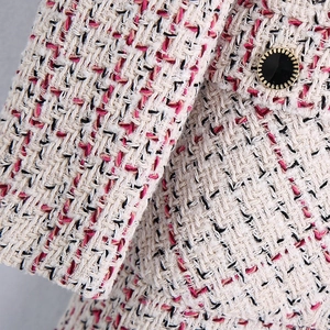 Detail of pink tweed jacket showing textured weave and a gold-edged decorative button