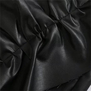 Macro detail of high-waist black faux leather skirt showing fine lychee grain texture