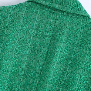Macro shot of emerald green tweed fabric showing premium woven texture and seam details