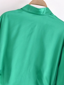 Detailansicht des Rückenkragens eines grünen Satin-Langarmhemdkleides mit seidiger Textur