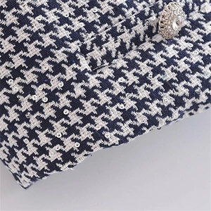 Detail of blue and white houndstooth tweed fabric with silver sequins and jewel button