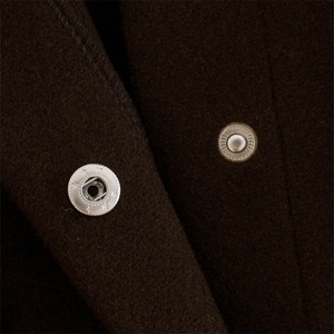 Detailed macro view of metal snap button on thick dark brown wool blend shirt jacket