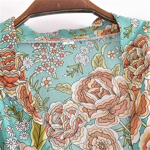 Detail of mint green floral rayon top with orange flowers and delicate lace trim edge