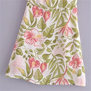 Detailed close-up of tropical floral and leaf prints on a white summer mini dress