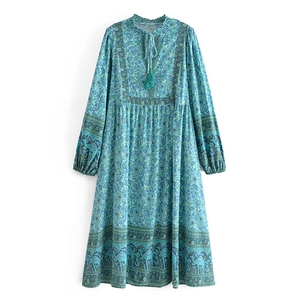 Détail du col en V avec pompons verts et imprimé ethnique sur une robe en coton bleue
