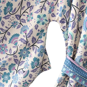 Détail de robe à col en V montrant le tissu léger et les motifs floraux bleus