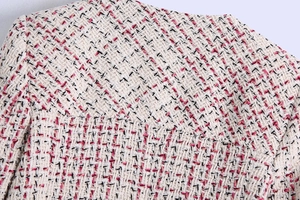 Detailed macro view of pink and white tweed fabric texture and stitching on the coat shoulder