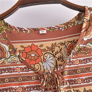 Détail de l'encolure en V avec pompons et imprimé floral vintage sur une robe à manches longues