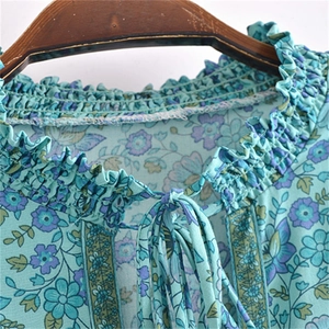 Détail du col en V à volants avec liens et imprimé fleuri sur une robe en coton