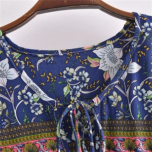 Detail of the V-neck with tassel ties on a blue floral printed bohemian dress