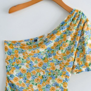 Detail view of the floral one-shoulder mini dress with an internal size S label