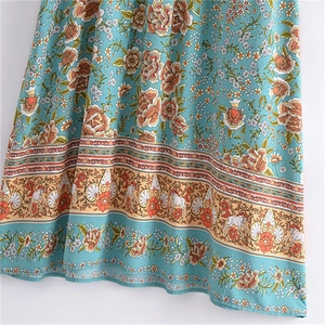 Détail d'une robe bohème turquoise avec motifs floraux et bordure à franges ethniques