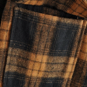 Close-up of the side pocket and thick flannel texture on the brown plaid shirt jacket