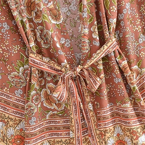 Dettaglio della stampa floreale boho su abito kimono rosso ruggine con lacci in vita