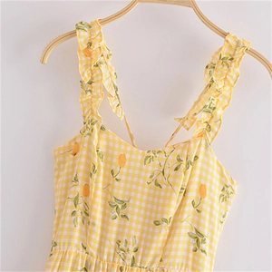 Robe d'été à carreaux jaunes avec imprimé citron et bretelles à volants sur un cintre bois