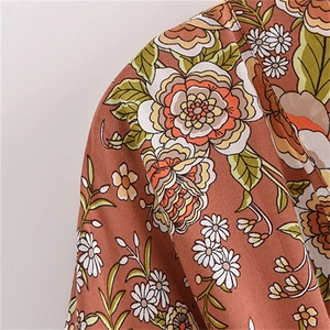 Dettaglio della stampa floreale boho su tessuto di cotone rosso bruno dell'abito