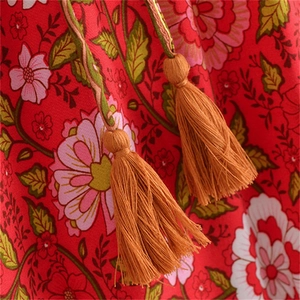 Dettaglio della gonna lunga rossa in cotone con stampa floreale e nappe boho chic