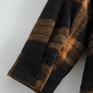 Detail of plaid cotton shirt cuff with premium stitching and black button closure